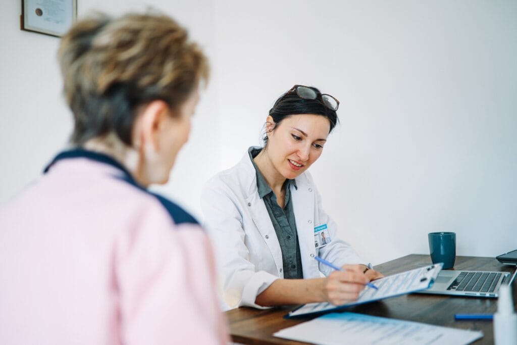 Woman Dr. with her patient, taking notes during appointment
